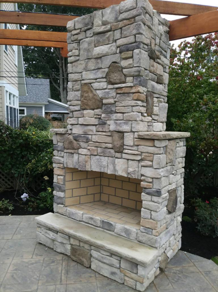 Example of a mid-sized trendy backyard stamped concrete patio design in Cleveland with a fireplace and a pergola