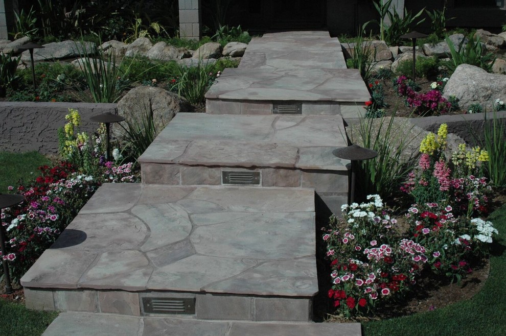 This is an example of a large tropical front yard partial sun formal garden in Phoenix with a garden path and natural stone pavers.