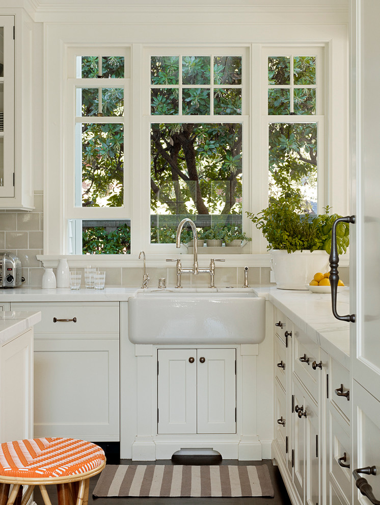 Photo of a traditional kitchen in San Francisco with a farmhouse sink, shaker cabinets, white cabinets, beige splashback and subway tile splashback.