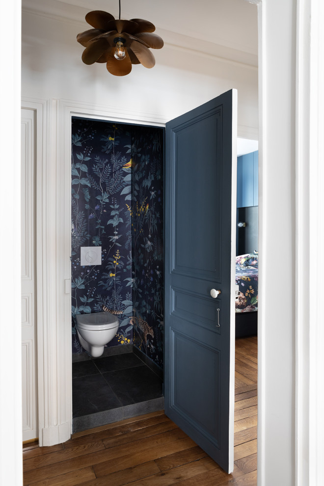 Photo of a world-inspired cloakroom in Paris with beaded cabinets, a wall mounted toilet, blue walls, slate flooring, grey floors, a built in vanity unit and wallpapered walls.
