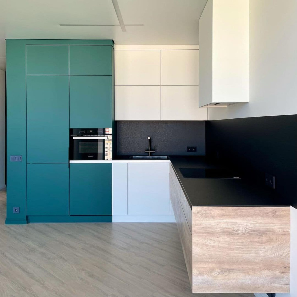 Large minimalist l-shaped medium tone wood floor and brown floor open concept kitchen photo in Moscow with a drop-in sink, flat-panel cabinets, green cabinets, solid surface countertops, black backsplash, porcelain backsplash, black appliances, no island and gray countertops