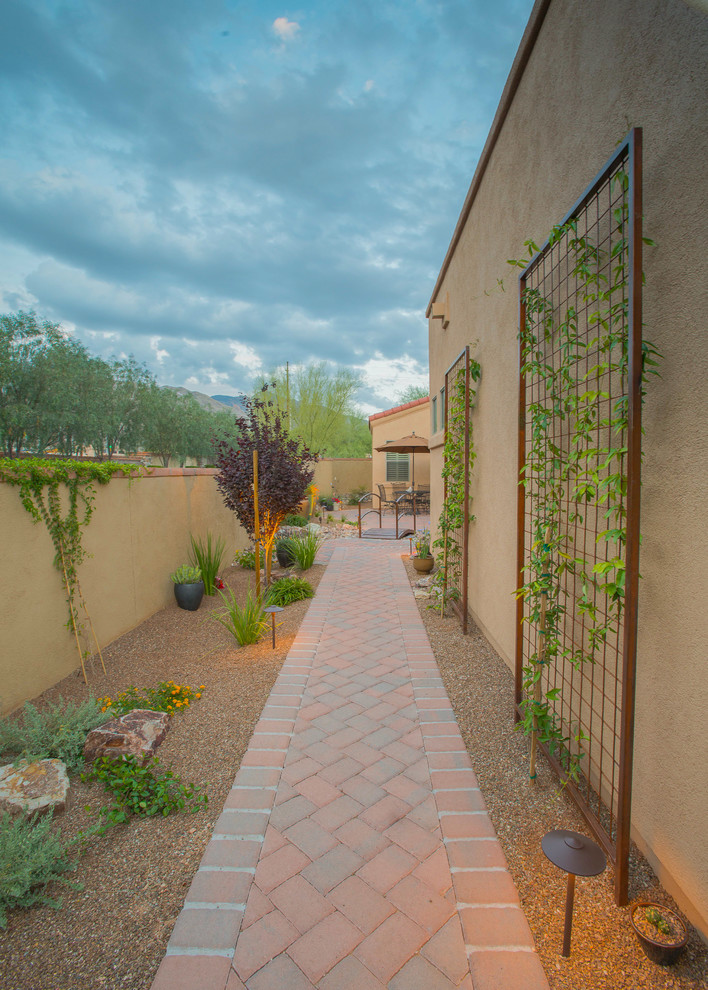 Photo of a mid-sized and desert look side yard partial sun xeriscape in Phoenix with brick pavers.