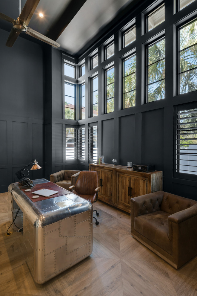 Источник вдохновения для домашнего уюта: большое рабочее место в морском стиле с черными стенами, отдельно стоящим рабочим столом, коричневым полом и панелями на части стены