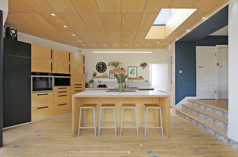 Exempel på ett mellanstort modernt vit vitt kök, med släta luckor, skåp i ljust trä, träbänkskiva, flerfärgad stänkskydd, stänkskydd i keramik, ljust trägolv, en köksö, brunt golv och svarta vitvaror
