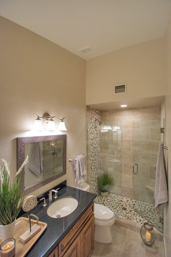 Photo of a mid-sized traditional master bathroom in Phoenix with beige tile, porcelain tile, beige walls, porcelain floors, beige floor, a hinged shower door, raised-panel cabinets, dark wood cabinets, an alcove shower, a two-piece toilet, an undermount sink and engineered quartz benchtops.