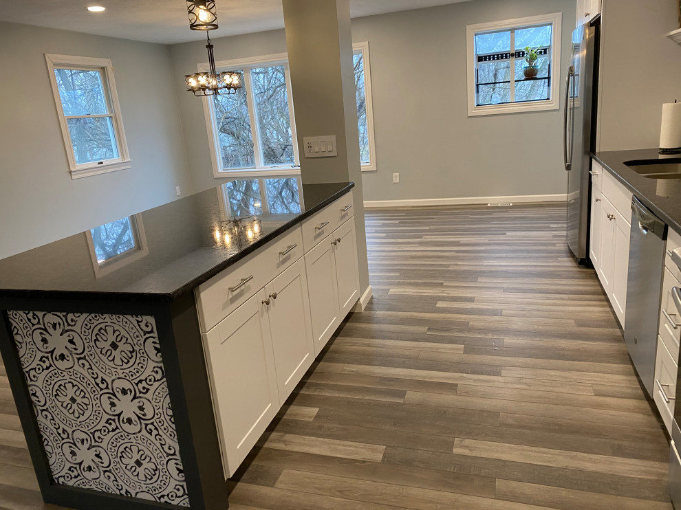Example of a large transitional l-shaped vinyl floor and gray floor open concept kitchen design in Cincinnati with an undermount sink, raised-panel cabinets, white cabinets, granite countertops, multicolored backsplash, ceramic backsplash, stainless steel appliances, an island and black countertops