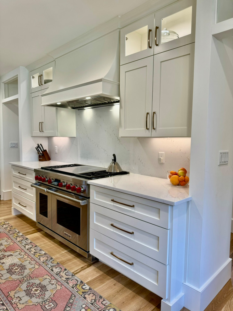 Inspiration for a mid-sized transitional l-shaped light wood floor, brown floor and wallpaper ceiling eat-in kitchen remodel in Atlanta with a farmhouse sink, shaker cabinets, white cabinets, granite countertops, white backsplash, stainless steel appliances, an island and white countertops