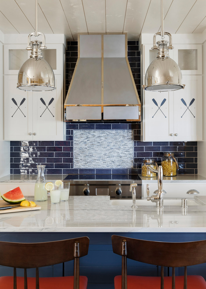 Inspiration for a mid-sized beach style single-wall open plan kitchen in Minneapolis with a farmhouse sink, shaker cabinets, white cabinets, marble benchtops, blue splashback, subway tile splashback, stainless steel appliances, with island, white benchtop and timber.