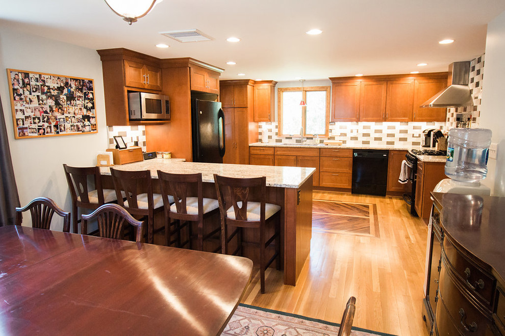 Eat-in kitchen - mid-sized transitional u-shaped medium tone wood floor eat-in kitchen idea in Boston with an undermount sink, recessed-panel cabinets, medium tone wood cabinets, granite countertops, black appliances, a peninsula, multicolored backsplash and subway tile backsplash