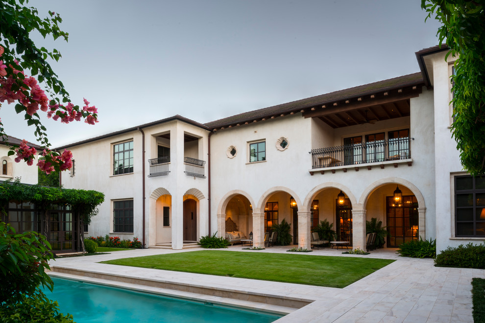 Photo of an expansive mediterranean two-storey stucco white house exterior in Houston with a hip roof and a tile roof.