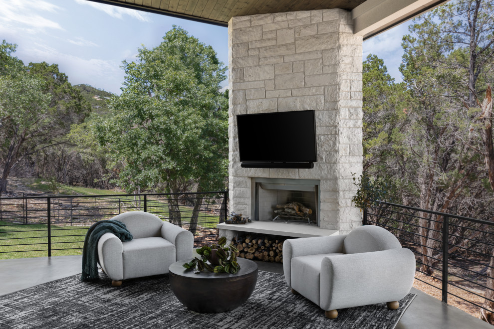Inspiration for a contemporary backyard verandah in Austin with with fireplace, stamped concrete and a roof extension.