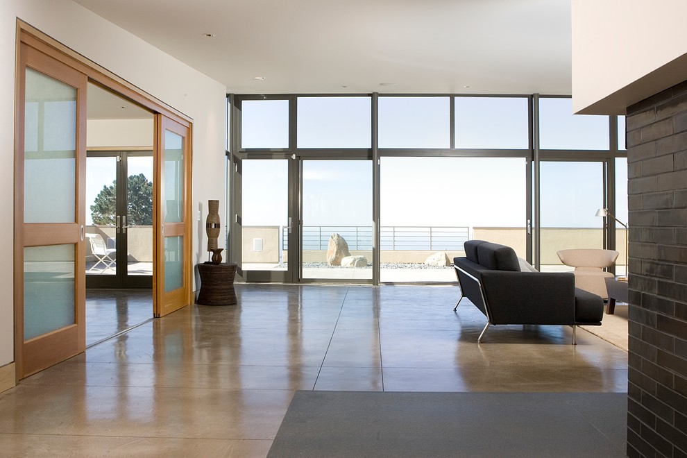 This is an example of a large contemporary open concept living room in San Francisco with concrete floors and white walls.