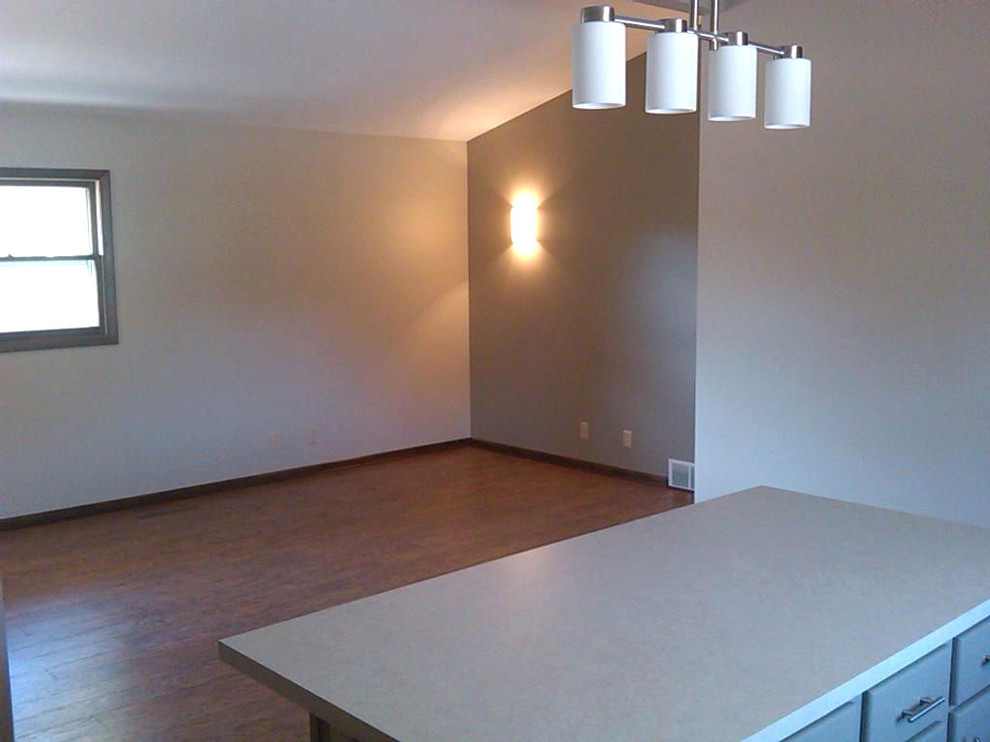 Example of a mid-sized l-shaped laminate floor and brown floor open concept kitchen design with a drop-in sink, flat-panel cabinets, gray cabinets, laminate countertops, beige backsplash, glass tile backsplash, white appliances, an island and beige countertops