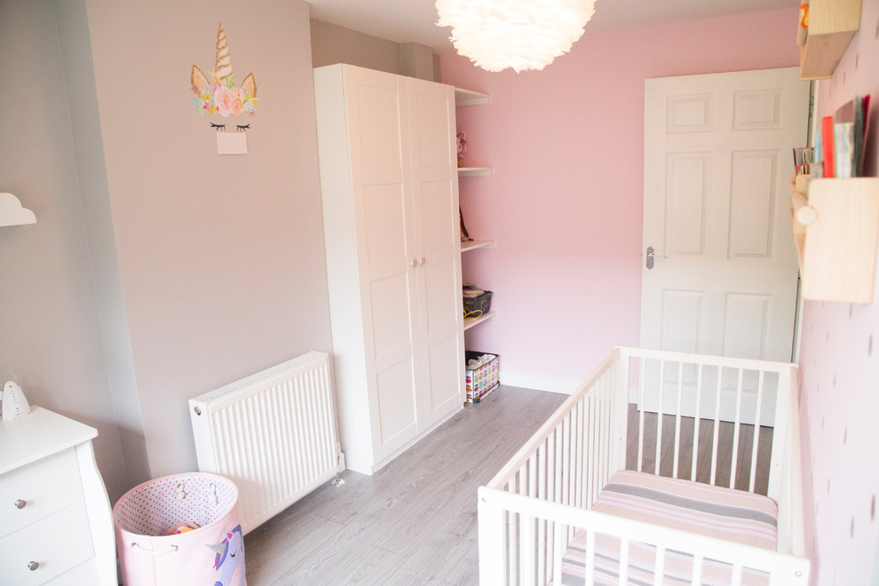 Mid-sized contemporary kids' room in Edinburgh with pink walls and laminate floors for girls.