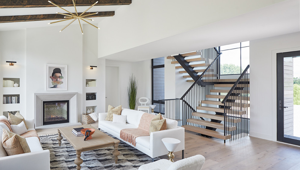 Inspiration for a large contemporary open concept light wood floor and exposed beam living room remodel in Grand Rapids with white walls, a standard fireplace and a concrete fireplace