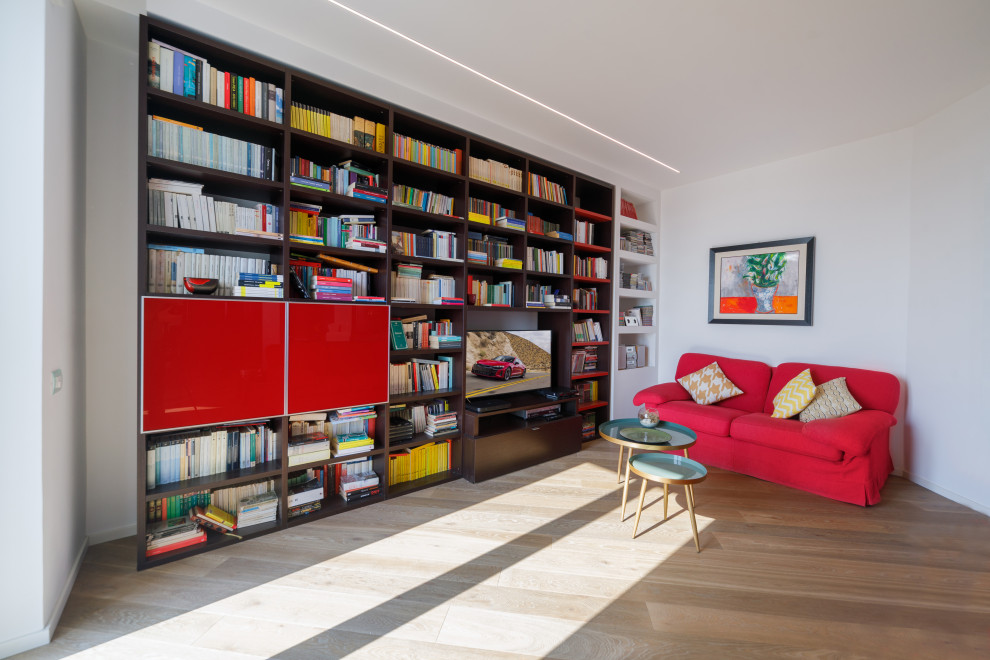 Mittelgroße, Offene Moderne Bibliothek mit weißer Wandfarbe, hellem Holzboden und TV-Wand in Sonstige