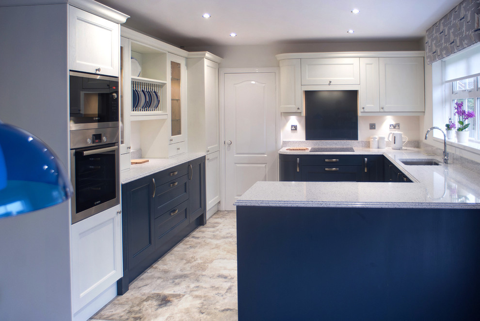 Photo of a mid-sized traditional u-shaped eat-in kitchen in Other with an integrated sink, shaker cabinets, blue cabinets, quartzite benchtops, blue splashback, glass sheet splashback, stainless steel appliances, vinyl floors, no island, multi-coloured floor and multi-coloured benchtop.