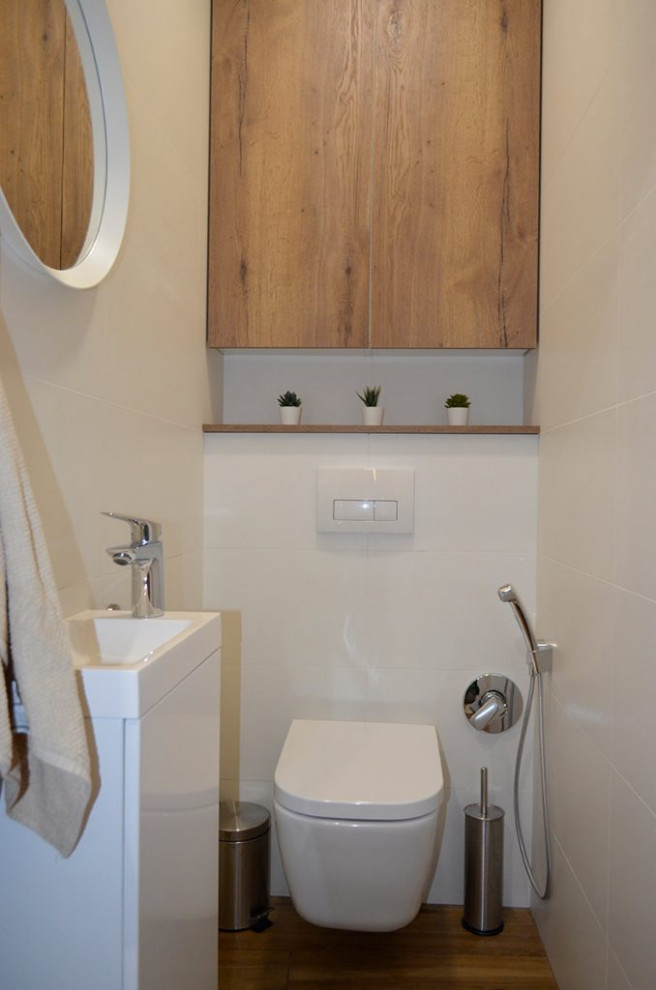 Bild på ett mellanstort funkis vit vitt toalett, med släta luckor, skåp i mellenmörkt trä, en vägghängd toalettstol, vit kakel, keramikplattor, vita väggar, klinkergolv i keramik, ett nedsänkt handfat, brunt golv och bänkskiva i akrylsten