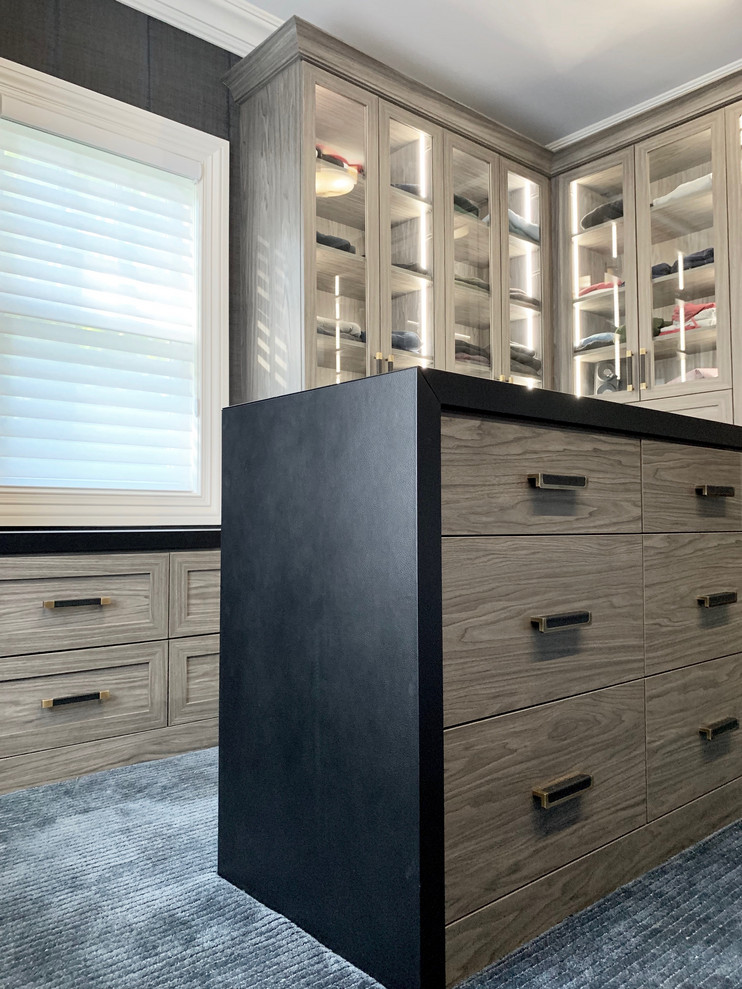This is an example of a large modern men's walk-in wardrobe in New York with flat-panel cabinets, grey cabinets, carpet and blue floor.