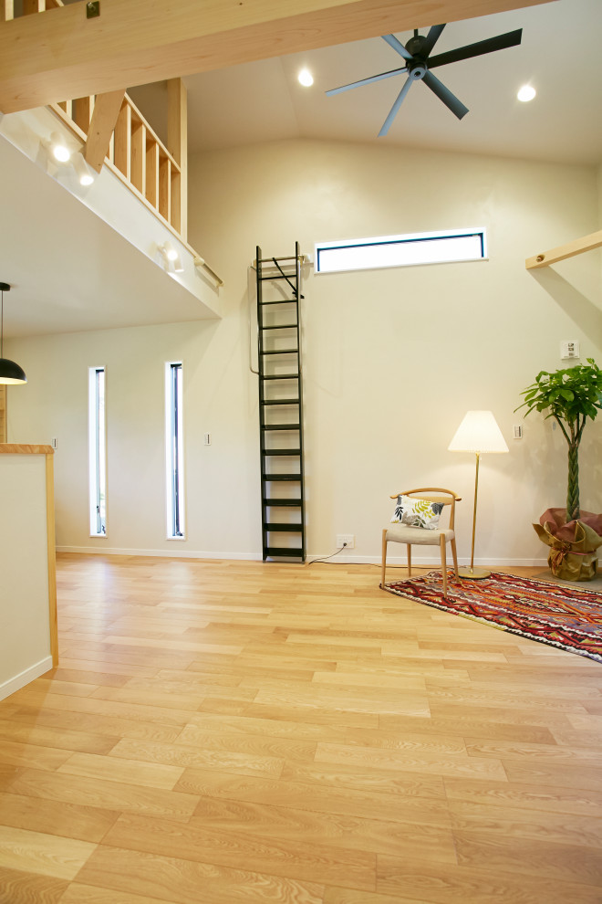 Imagen de sala de estar abierta con paredes grises, suelo de madera en tonos medios, suelo marrón y machihembrado