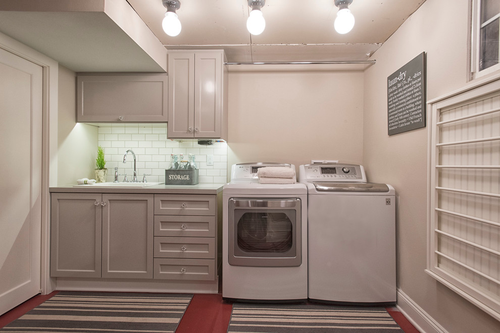This is an example of a mid-sized beach style dedicated laundry room in Portland with a drop-in sink, shaker cabinets, grey cabinets, laminate benchtops, grey walls, concrete floors and a side-by-side washer and dryer.
