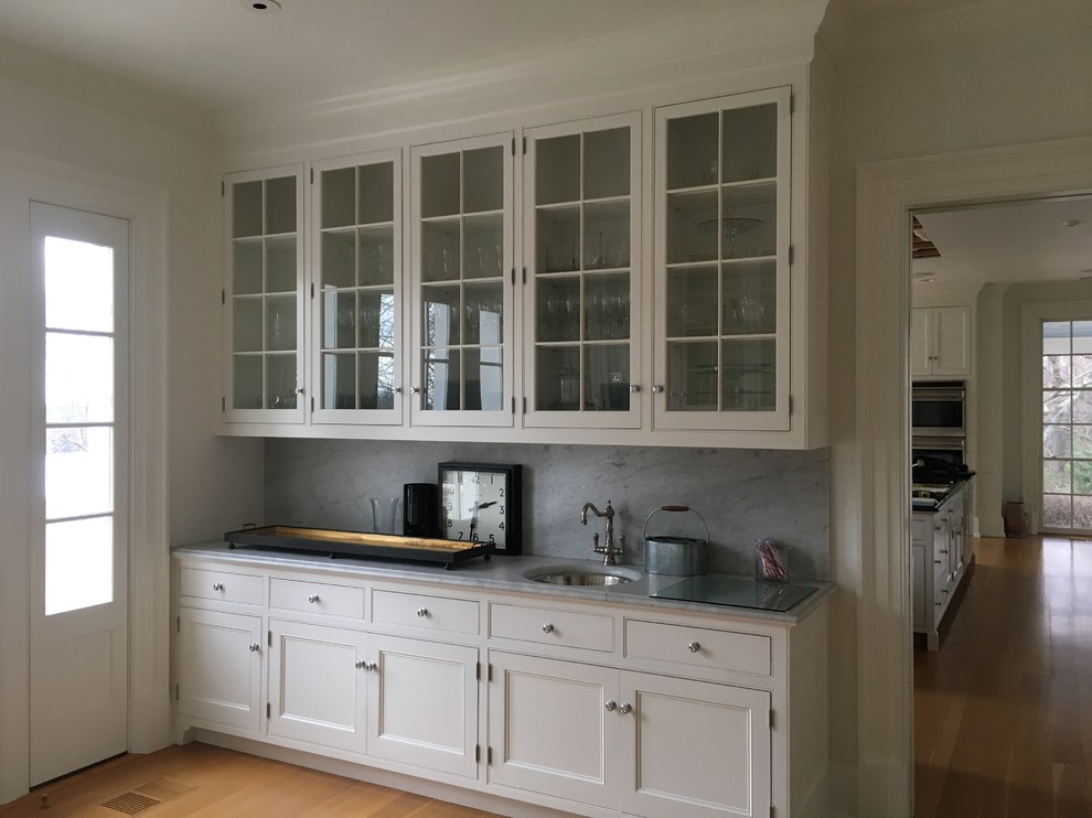 Design ideas for a large traditional galley separate kitchen in DC Metro with an undermount sink, flat-panel cabinets, white cabinets, terrazzo benchtops, grey splashback, stone slab splashback, panelled appliances, light hardwood floors and brown floor.