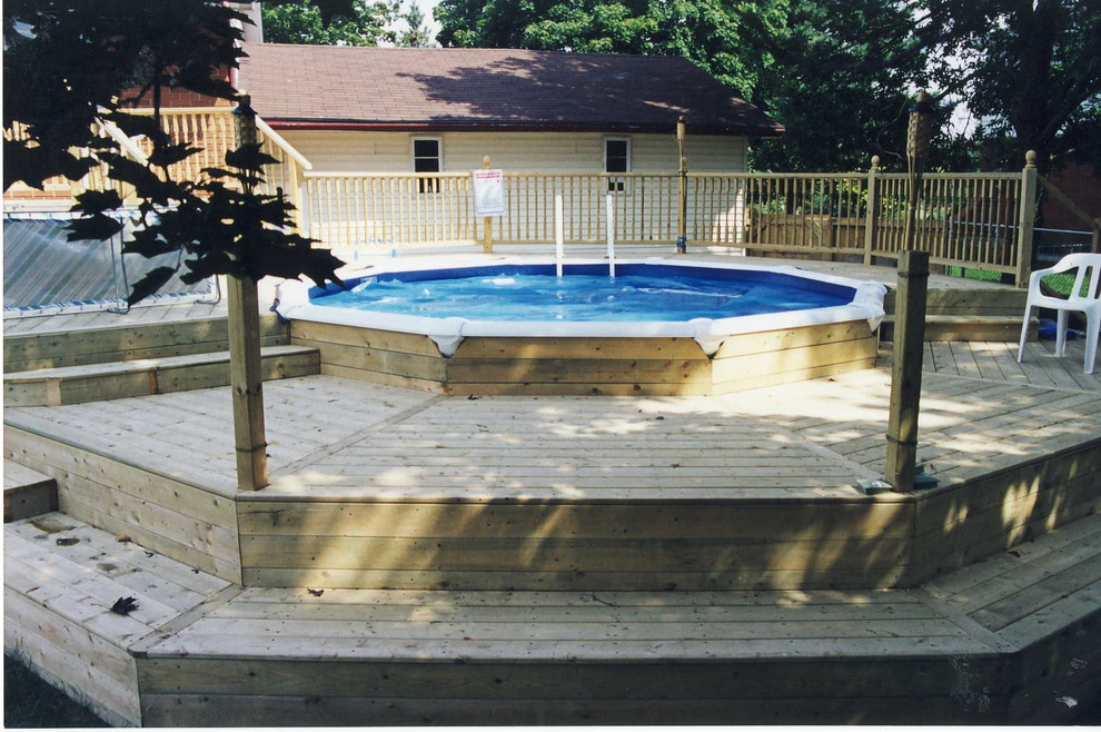 Design ideas for a mid-sized traditional backyard round aboveground pool in Toronto with decking.