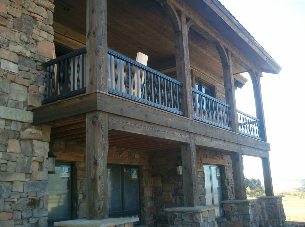 Large mountain style backyard deck photo with a roof extension