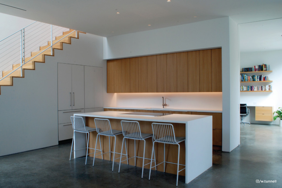 Photo of a large l-shaped kitchen/diner in Dallas with flat-panel cabinets, medium wood cabinets, concrete flooring, an island, grey floors and white worktops.