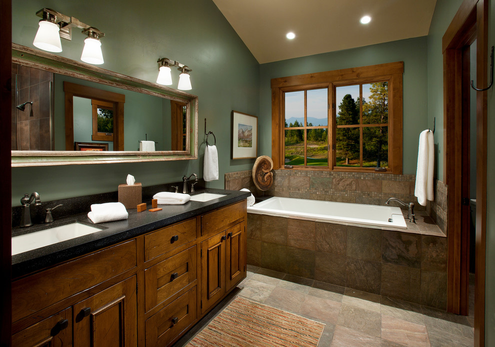 Inspiration for a country bathroom in Other with an undermount sink, recessed-panel cabinets, medium wood cabinets, a drop-in tub, brown tile, green walls and slate.