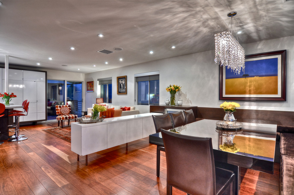 This is an example of a contemporary open plan dining in Orange County with white walls and dark hardwood floors.