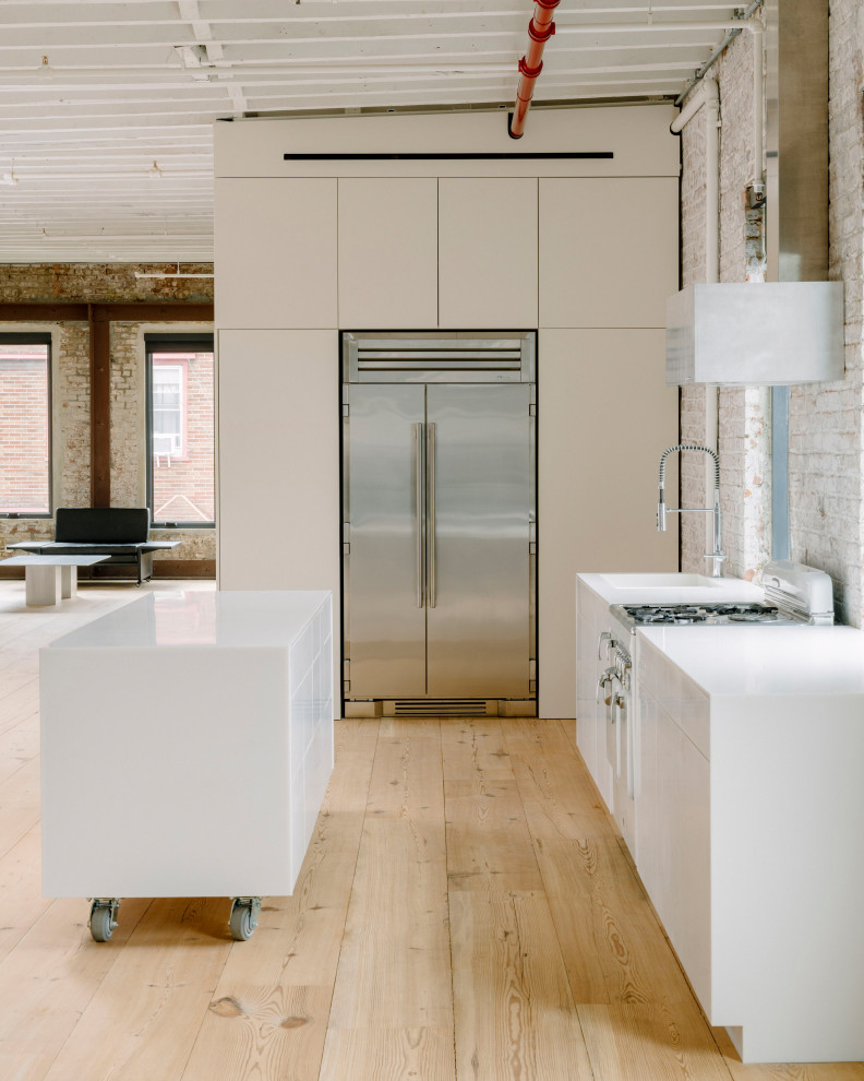 Inspiration for a large contemporary kitchen in New York with an integrated sink, white cabinets, brick splashback, stainless steel appliances, light hardwood floors, with island, beige floor, white benchtop and exposed beam.