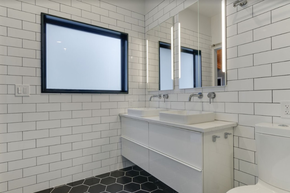 Mid-sized modern master bathroom in Portland with flat-panel cabinets, white cabinets, a freestanding tub, a shower/bathtub combo, a two-piece toilet, white tile, subway tile, white walls, porcelain floors, a vessel sink, engineered quartz benchtops, black floor, a hinged shower door and white benchtops.