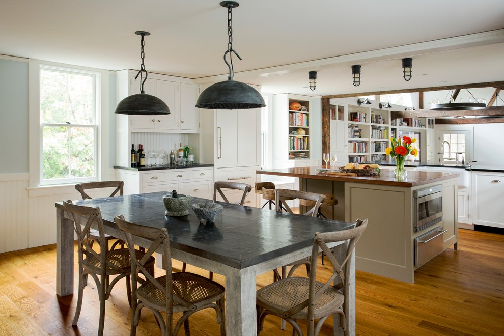 Inspiration for a large country l-shaped eat-in kitchen in Boston with shaker cabinets, white cabinets, white splashback, stainless steel appliances, medium hardwood floors, with island and a farmhouse sink.