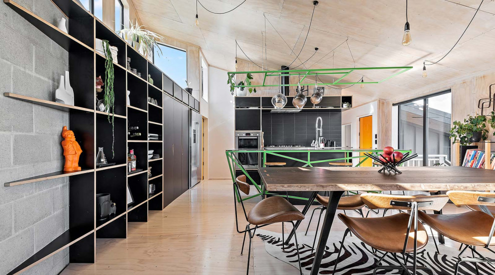 Design ideas for a mid-sized industrial galley eat-in kitchen in Wellington with an integrated sink, recessed-panel cabinets, black cabinets, stainless steel benchtops, black splashback, ceramic splashback, stainless steel appliances, plywood floors, with island and timber.