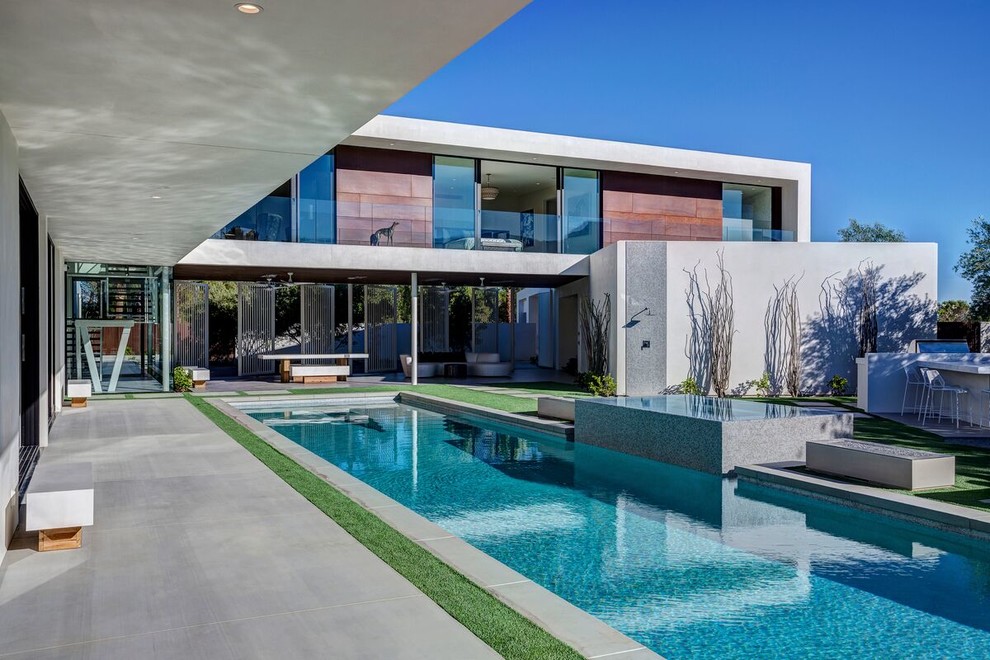 Photo of a contemporary rectangular lap pool in Los Angeles with concrete slab and a hot tub.
