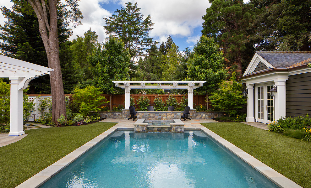 Large traditional front yard rectangular pool in San Francisco with natural stone pavers and a hot tub.
