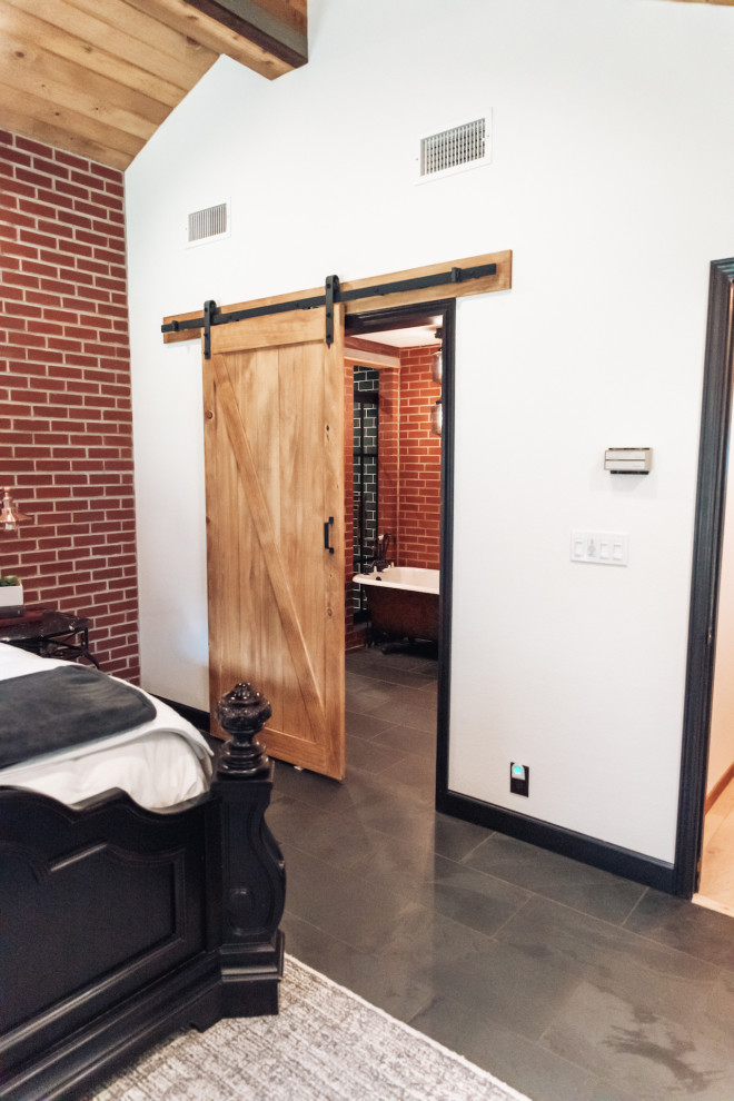 На фото: спальня в стиле лофт с серым полом, деревянным потолком и кирпичными стенами с
