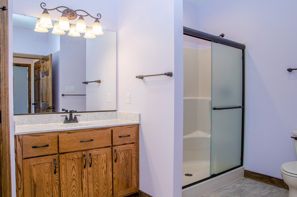 Inspiration for a mid-sized transitional master bathroom in Richmond with flat-panel cabinets, medium wood cabinets, an alcove shower, a one-piece toilet, purple walls, laminate floors, an integrated sink, laminate benchtops, beige floor, a sliding shower screen and beige benchtops.