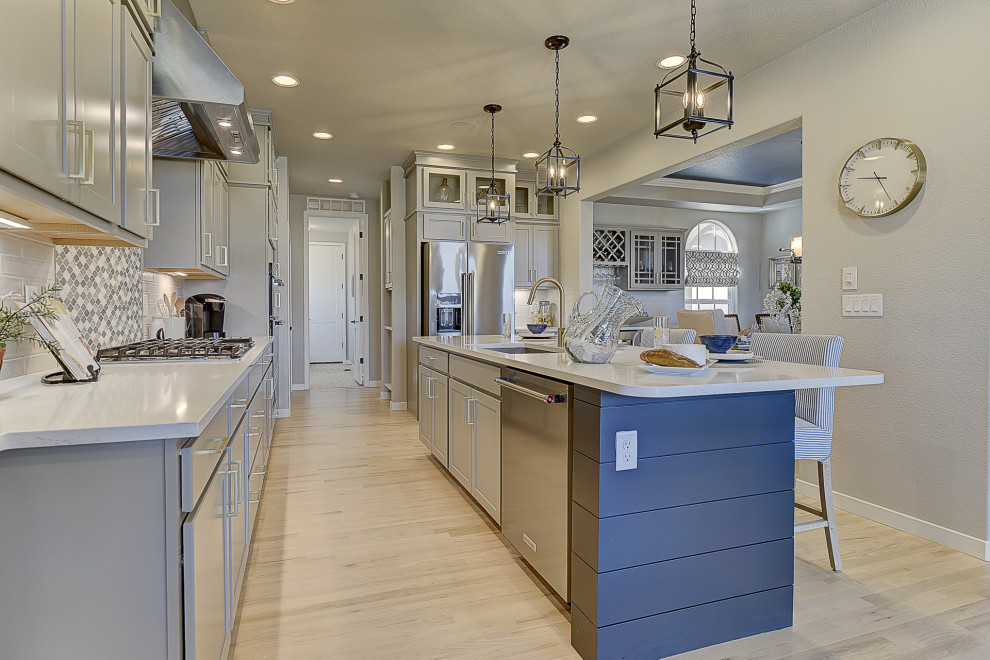 Design ideas for a beach style galley eat-in kitchen in Denver with an undermount sink, solid surface benchtops, grey splashback, stainless steel appliances, light hardwood floors, with island and white benchtop.