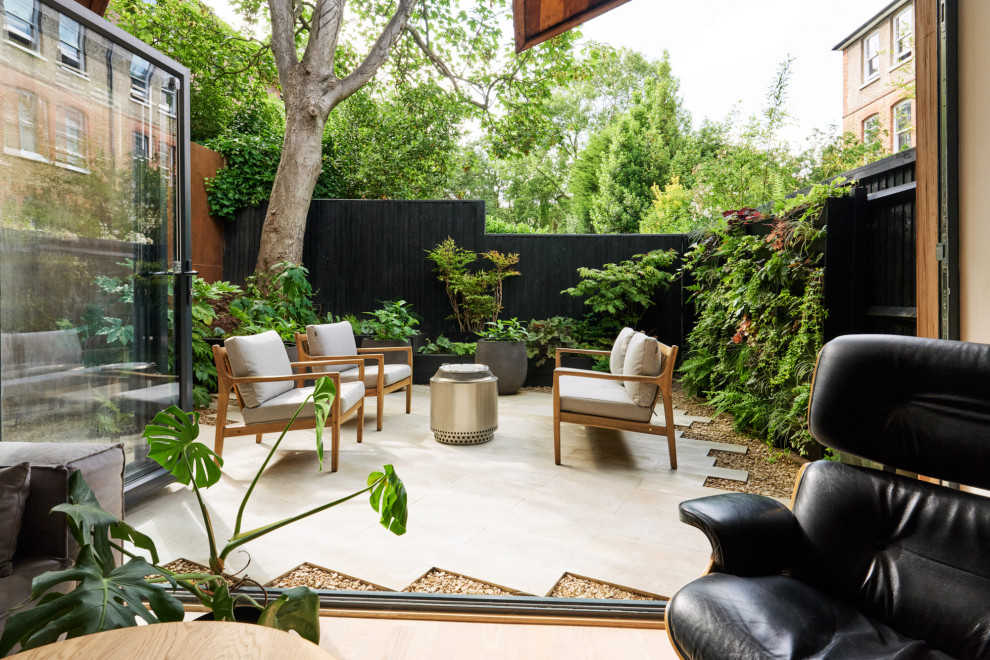 Design ideas for a small modern backyard partial sun garden for summer in London with natural stone pavers and a wood fence.
