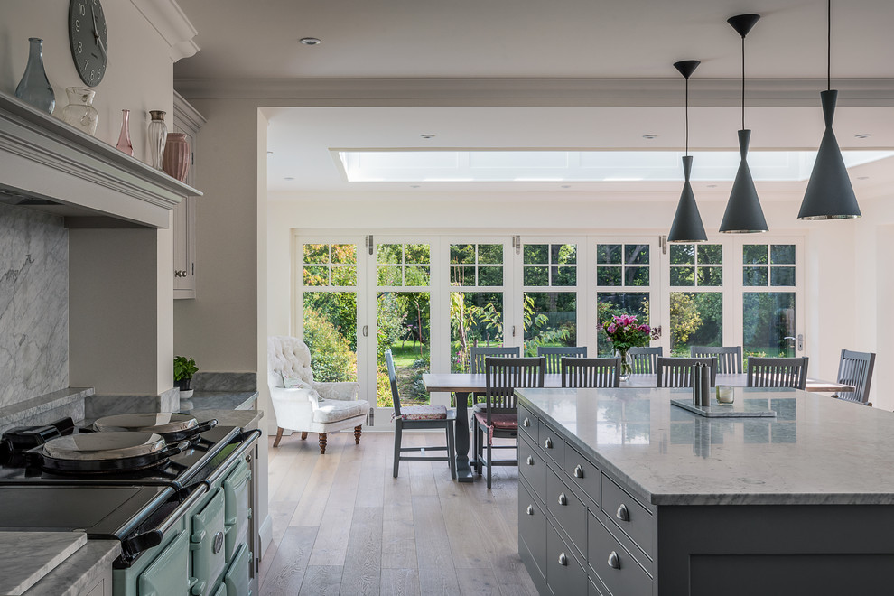 This is an example of a large transitional u-shaped eat-in kitchen in Surrey with a farmhouse sink, grey cabinets, marble benchtops, grey splashback, stone slab splashback, panelled appliances, medium hardwood floors, with island and flat-panel cabinets.