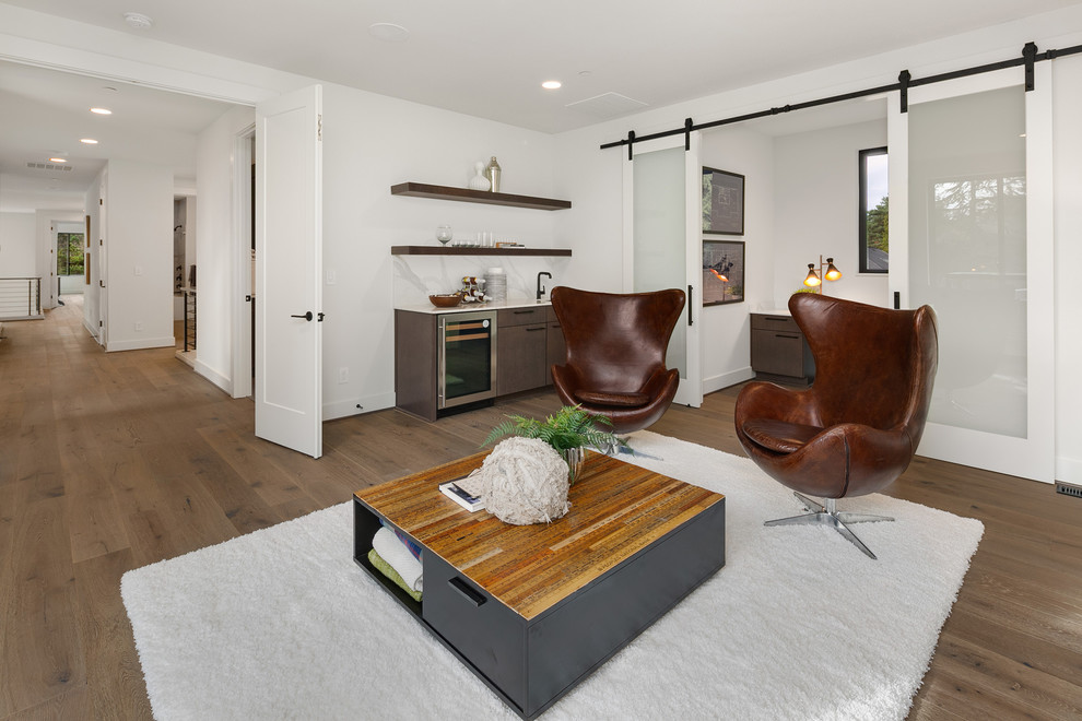This is an example of a large contemporary open concept family room in Seattle with a game room, white walls, medium hardwood floors, no tv and grey floor.