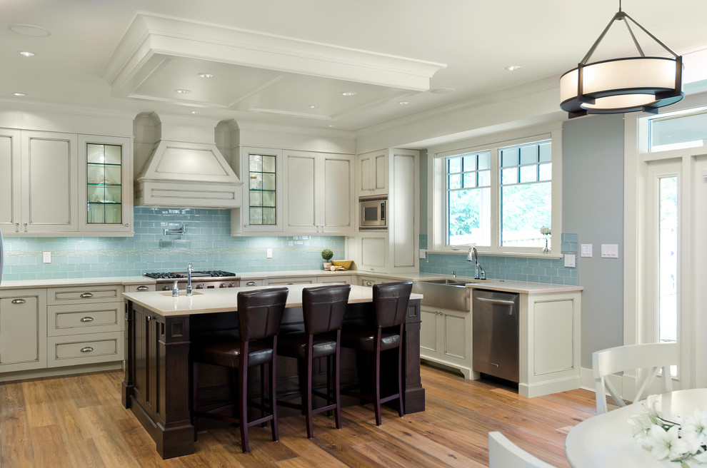 Design ideas for a traditional kitchen in Vancouver with a farmhouse sink, recessed-panel cabinets, white cabinets, blue splashback, glass tile splashback and stainless steel appliances.
