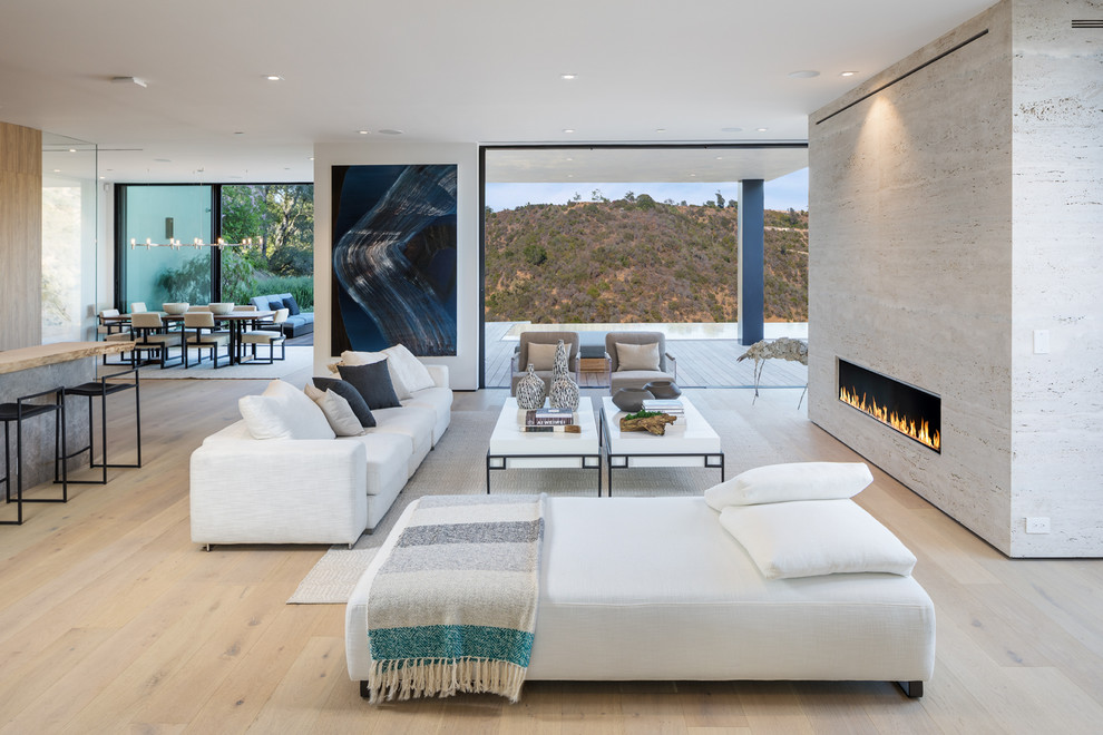 Inspiration for a contemporary open concept living room in Los Angeles with white walls, light hardwood floors, a ribbon fireplace and beige floor.