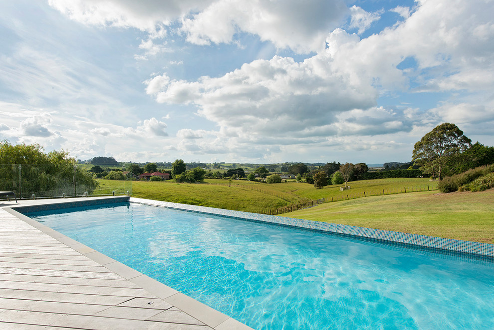Photo of a contemporary backyard rectangular infinity pool in Other with decking.