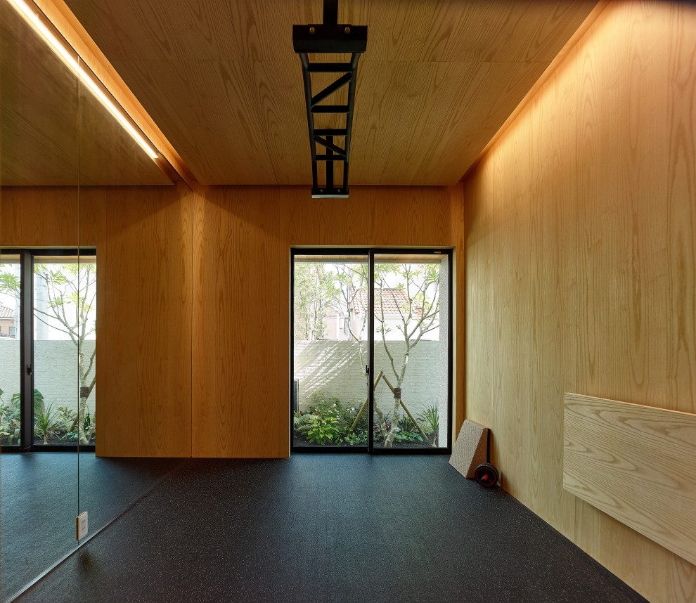 Photo of a mid-sized asian home weight room in Kobe with brown walls, black floor and wood.