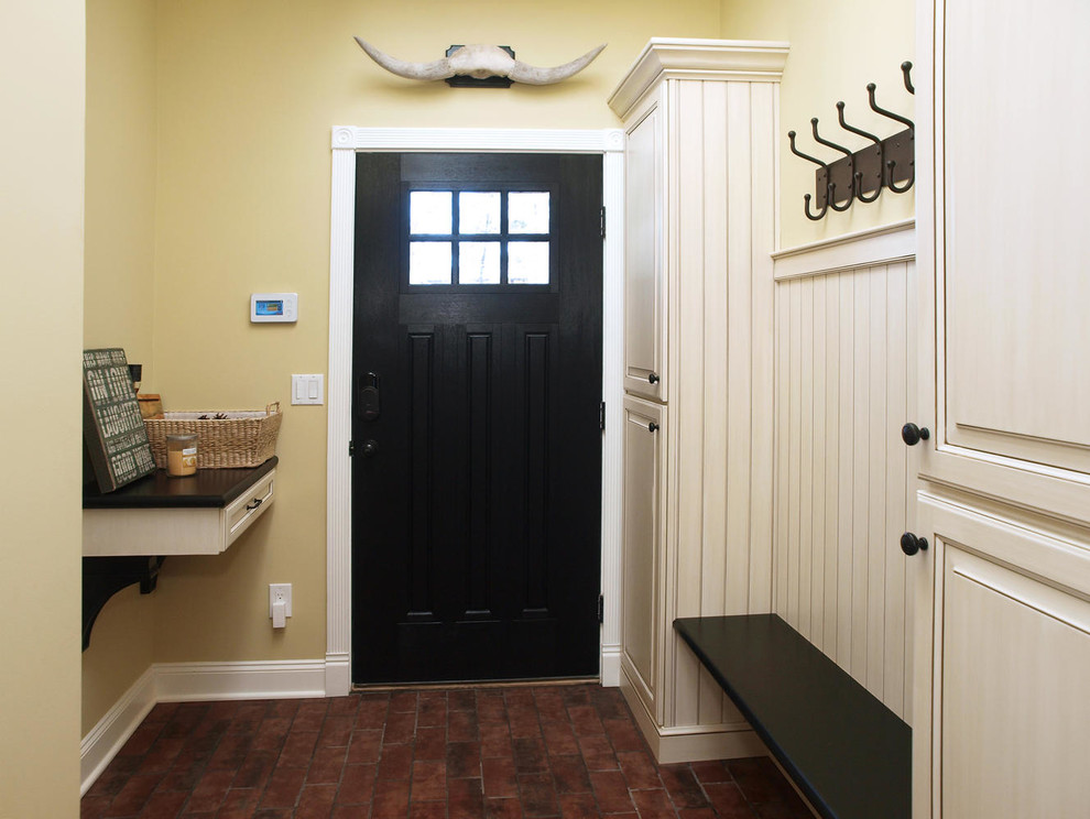 Design ideas for a small mudroom in New York with yellow walls and a black front door.