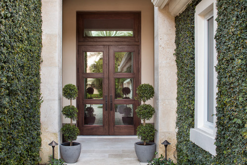 Classic modern outdoor entrance with custom double doors. Travertine tiles and pavers. Mature English Ivy on the exterior.