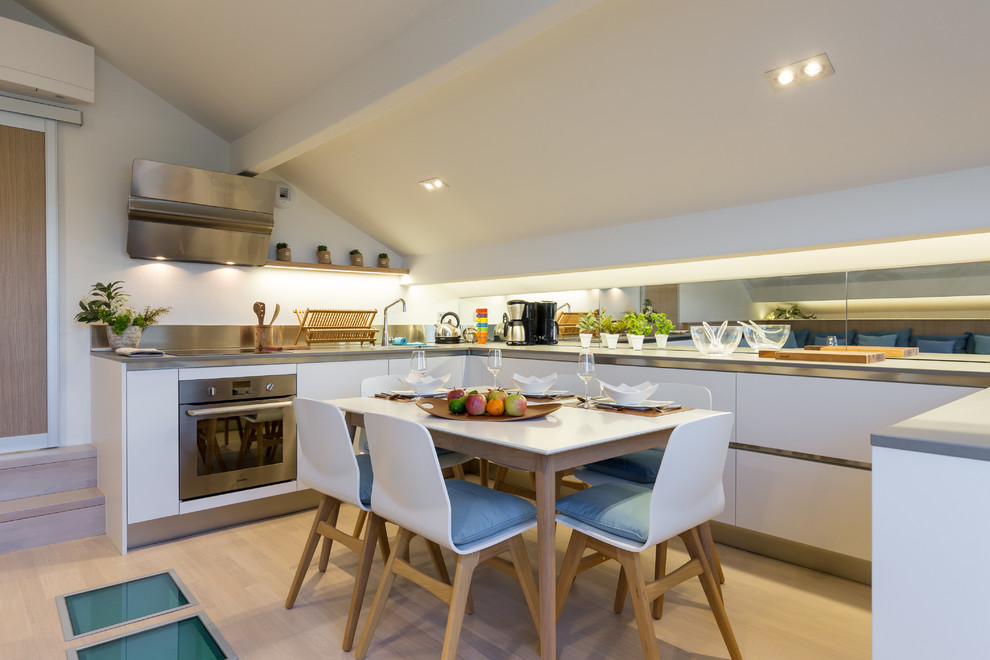 Photo of a mid-sized contemporary u-shaped eat-in kitchen in Nice with white cabinets, panelled appliances and light hardwood floors.